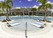 Thumbnail 27 of 29 - a large swimming pool with white chairs and a building in the background