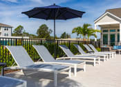 Thumbnail 11 of 92 - a row of lounge chairs and umbrellas on a patio with a house