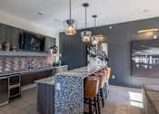 Thumbnail 23 of 31 - a kitchen with a long bar with chairs and a television
