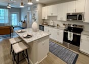 Thumbnail 28 of 30 - A kitchen with a white countertop and a stove top oven.