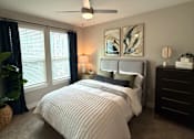 Thumbnail 27 of 30 - A bedroom with a large bed and a ceiling fan.