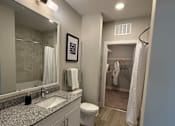 Thumbnail 25 of 30 - A bathroom with a sink, mirror, toilet, and shower.