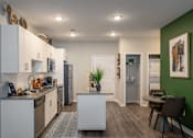 Thumbnail 3 of 31 - a kitchen and dining room with white cabinets and stainless steel appliances and a green wall