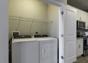 Thumbnail 10 of 29 - a washer and dryer in a laundry room with a kitchen in the background