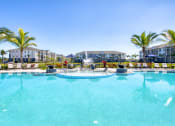 Thumbnail 22 of 54 - a large swimming pool with palm trees and buildings in the background