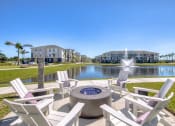 Thumbnail 25 of 54 - a fire pit and chairs in front of a pond with a fountain