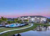 Thumbnail 7 of 54 - a large building with a pool and a lake at dusk