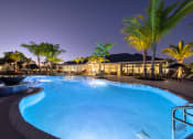 Thumbnail 11 of 54 - a swimming pool at night with palm trees and a building in the background