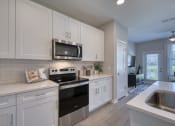 Thumbnail 45 of 54 - an open kitchen with white cabinets and a black stove and microwave