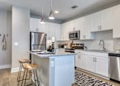 Thumbnail 58 of 62 - A kitchen with a white island and stainless steel appliances.