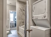 Thumbnail 56 of 62 - A white washing machine is in a bathroom next to a shower.