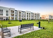 Thumbnail 39 of 62 - A park with benches and grass in front of apartment buildings.