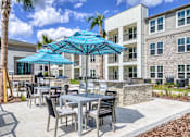 Thumbnail 1 of 62 - A patio with a table and chairs under a blue umbrella.