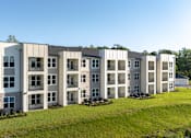 Thumbnail 36 of 62 - A row of modern apartment buildings with green lawns in front.