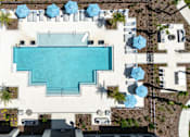 Thumbnail 32 of 62 - An aerial view of a swimming pool surrounded by lounge chairs and umbrellas.