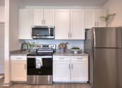 Thumbnail 90 of 92 - a kitchen with stainless steel appliances and white cabinets