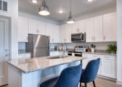 Thumbnail 80 of 92 - a kitchen with a marble counter top and blue chairs