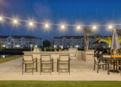 Thumbnail 50 of 92 - a patio with tables and chairs and a fire pit at night