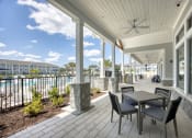 Thumbnail 24 of 92 - a covered porch with a table and chairs and a view of the water