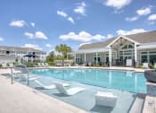 Thumbnail 30 of 92 - a swimming pool with white chairs and a building in the background