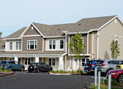 Thumbnail 4 of 22 - A large two-story building with a parking lot in front.