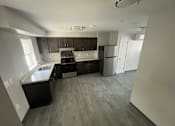 Thumbnail 15 of 22 - A kitchen with a black counter top and a white fridge.