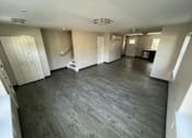 Thumbnail 13 of 22 - A large empty room with wooden floors and white walls.