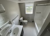 Thumbnail 10 of 22 - A white bathroom with a toilet, sink, and bathtub.