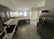Thumbnail 20 of 22 - A kitchen with a black refrigerator and a black stove top oven.