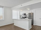 Thumbnail 12 of 50 - a white kitchen with a large island and stainless steel refrigerator at The Zenith, Baltimore, MD, 21201