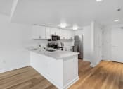 Thumbnail 13 of 50 - a white kitchen with a large island and a stainless steel refrigerator at The Zenith, Baltimore, 21201