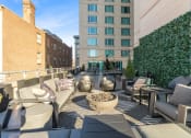 Thumbnail 44 of 50 - a rooftop patio with couches and chairs and a fire pit at The Zenith, Baltimore, MD