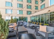 Thumbnail 46 of 50 - an outdoor patio with chairs and tables and a building in the background at The Zenith, Baltimore, MD