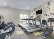 Thumbnail 34 of 35 - a gym with four treadmills and a television at Madison at Eden Brook, Columbia
