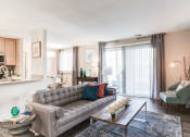 Thumbnail 9 of 33 - a living room with a gray couch and a coffee table in front of a sliding glass door at Ellicott Grove, Ellicott City Maryland