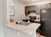 Thumbnail 4 of 28 - a kitchen with granite countertops and black appliances at Hamilton at Kings Place, Columbia, MD