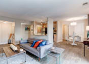 Thumbnail 8 of 33 - a living room with a couch table and chairs and a kitchen in the background at Ellicott Grove, Ellicott City