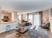 Thumbnail 7 of 33 - a living room with a couch coffee table and chairs and a kitchen in the background at Ellicott Grove, Maryland