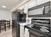 Thumbnail 12 of 33 - A black fridge and microwave in a kitchen with a stove and dining table.at Riviera Park, Chandler Arizona