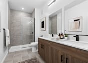 Thumbnail 5 of 8 - A modern bathroom with a walk-in shower and double sinks.