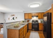 Thumbnail 1 of 54 - a kitchen with black appliances and wooden cabinets at Villages at Morgan Metro, Landover, MD 20785