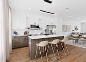 Thumbnail 1 of 8 - A modern kitchen with a bar stool in front of it.