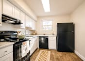 Thumbnail 2 of 24 - A black refrigerator stands in a kitchen with white cabinets and a black stove ighland Ridge Apartments, Capitol Heights, MD, 20743