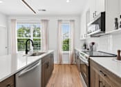 Thumbnail 2 of 8 - A modern kitchen with white countertops and wooden floors.