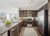 Thumbnail 3 of 45 - A modern kitchen with dark wood cabinets and stainless steel appliances at Aspire Apollo, Camp Springs, Maryland
