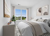Thumbnail 4 of 8 - A bedroom with a large bed and a window overlooking a green landscape.
