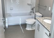 Thumbnail 8 of 10 - A white toilet sits next to a walk-in shower in a bathroom.