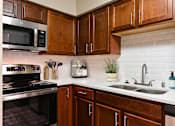 Thumbnail 4 of 24 - A kitchen with brown cabinets at Poplar Glen Apartments, Columbia, Maryland.