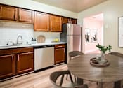 Thumbnail 1 of 45 - A kitchen with a table and chairs in the foreground and a framed picture on the wall at Poplar Glen Apartments, Columbia, MD, 21044.
