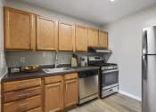 Thumbnail 3 of 6 - an empty kitchen with wooden cabinets and stainless steel appliances at Earle Manor Apartments, Wheaton, MD